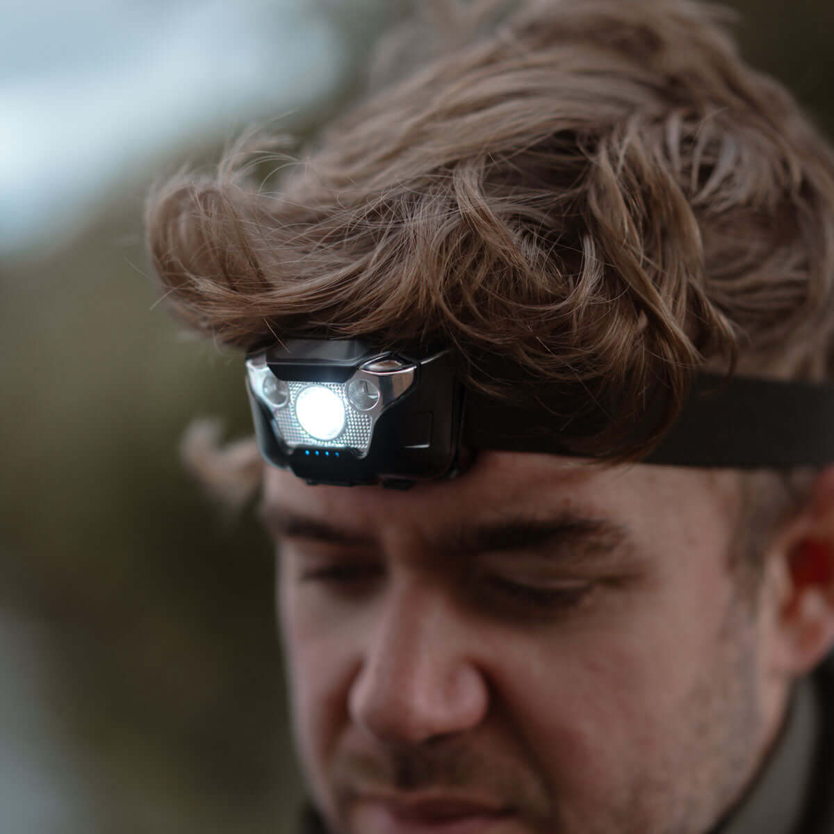 A man wearing a Dual Power 350 Headtorch, focused on the light while outdoors.