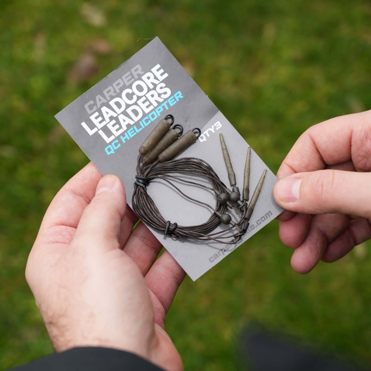 Person holding a pack of helicopter leadcore leaders ready for use while fishing outdoors.