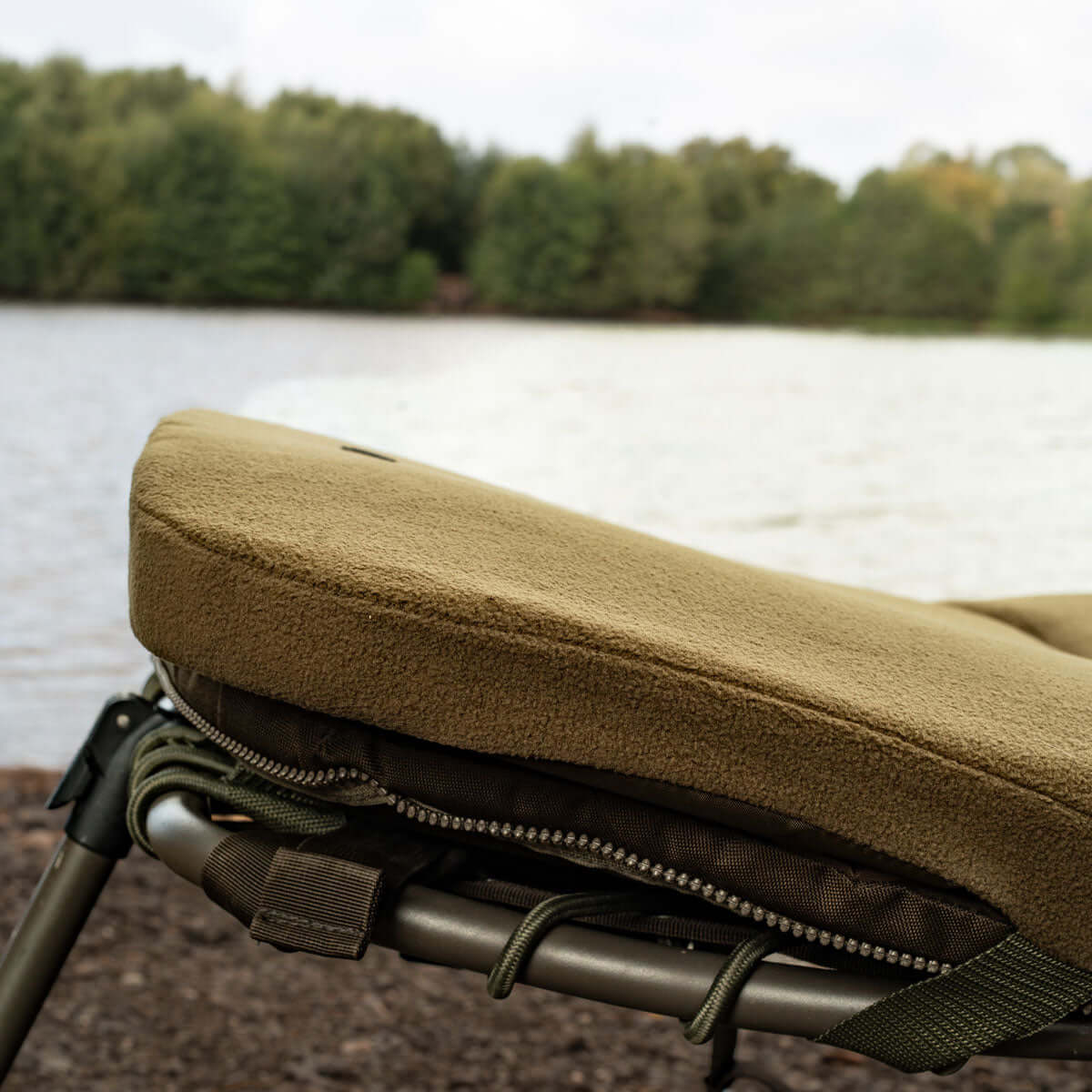 Close-up of a Memory Foam Bedchair Topper with fleece cover, set by a serene lakeside.