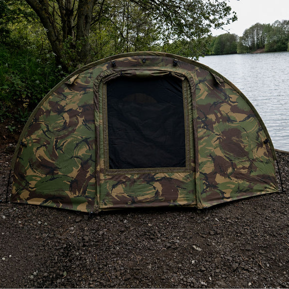 DPM Speedflex overwrap tent by the water, showcasing its camouflage design and spacious entrance.