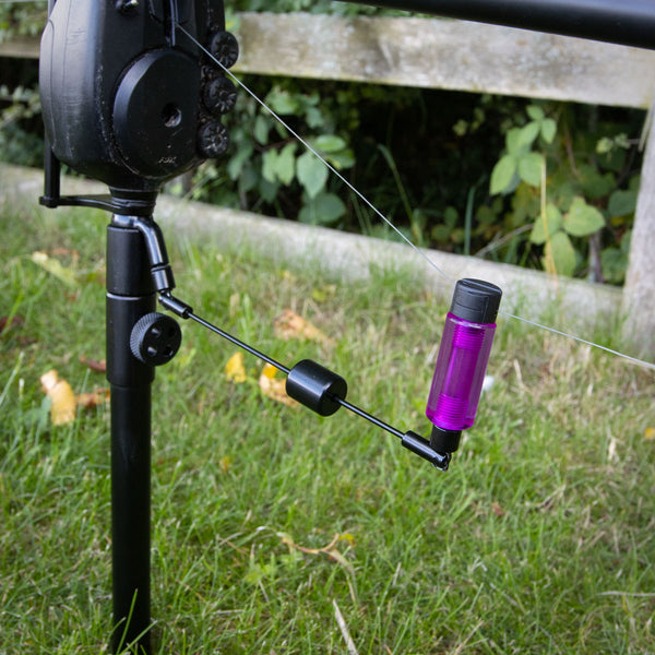 Weighted Swinger Arms attached to fishing rod with purple sliding weight and black rod holder in grass.